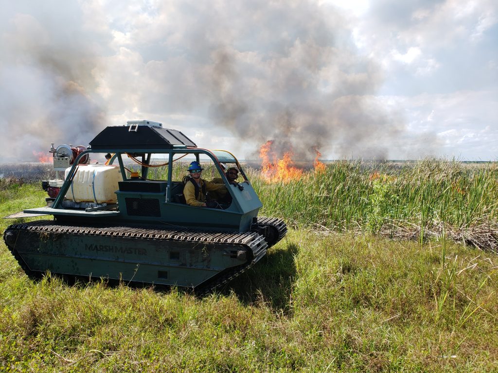District staff monitor a prescribed fire from a Marsh Master