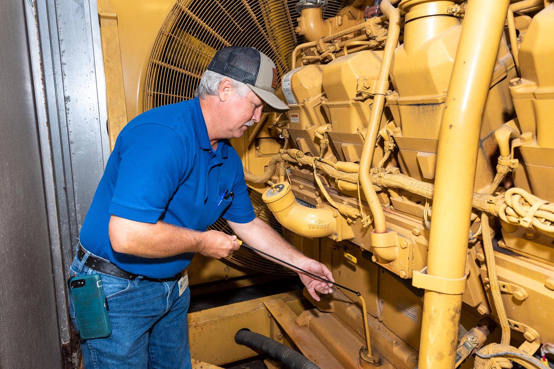 A District staff member conducts maintenance on a gas-powered generato