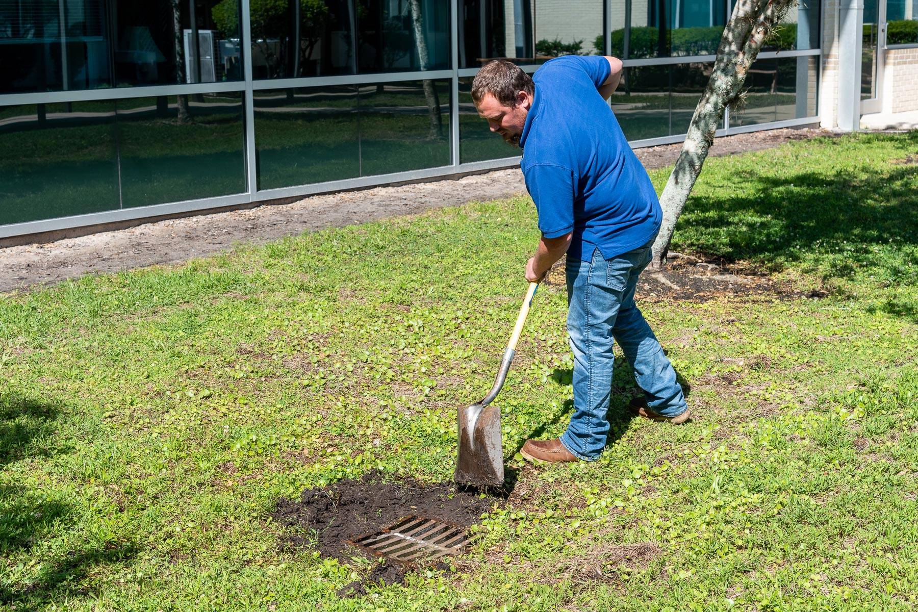 A District staff member ensures a drainage outlet is cleared of vegetation growth