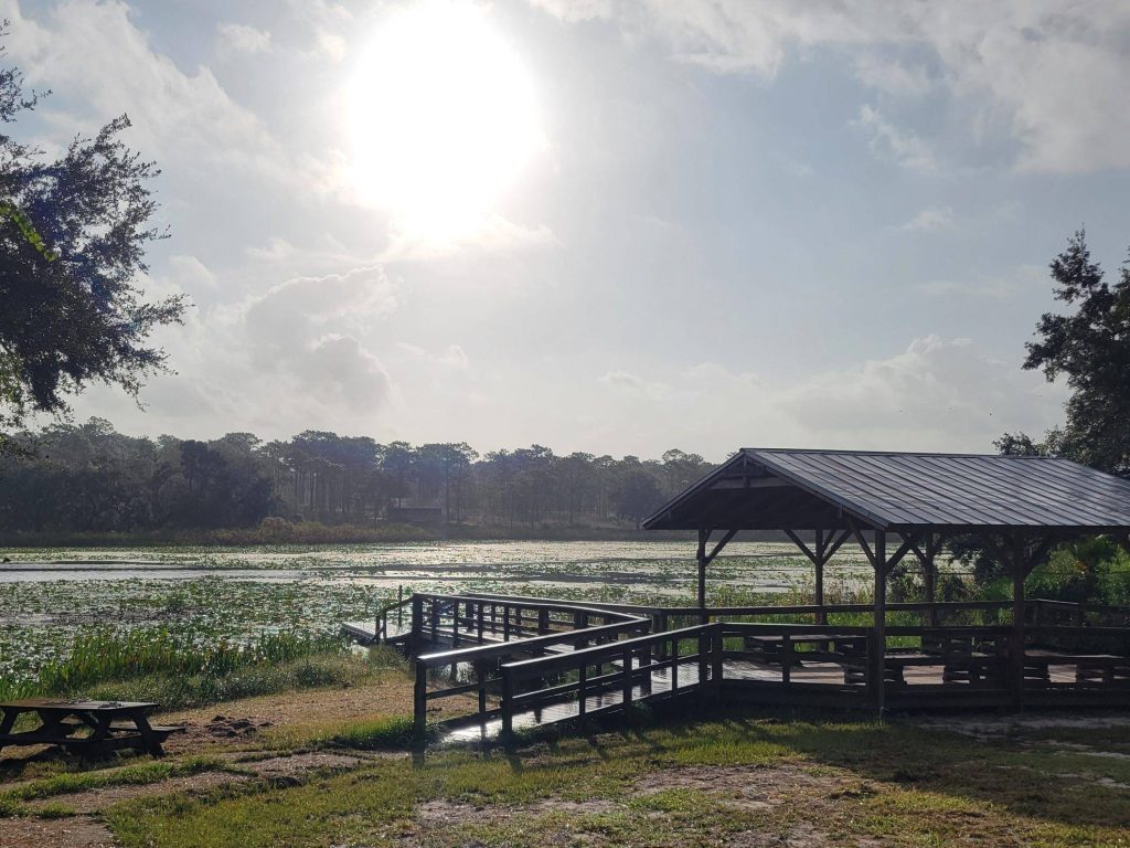 Sun in the sky over a gazebo next to a lake