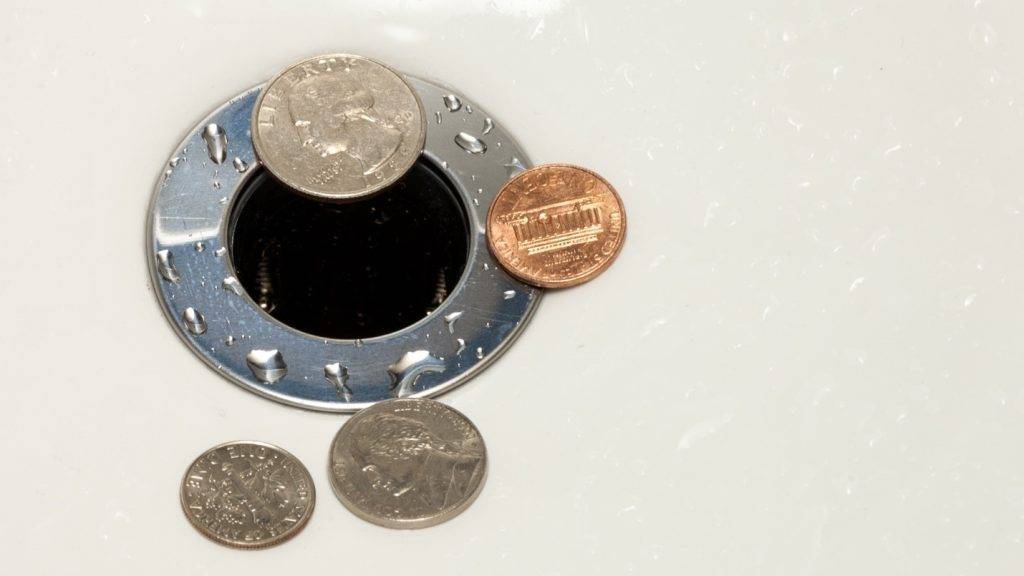 Coins lying next to a drain