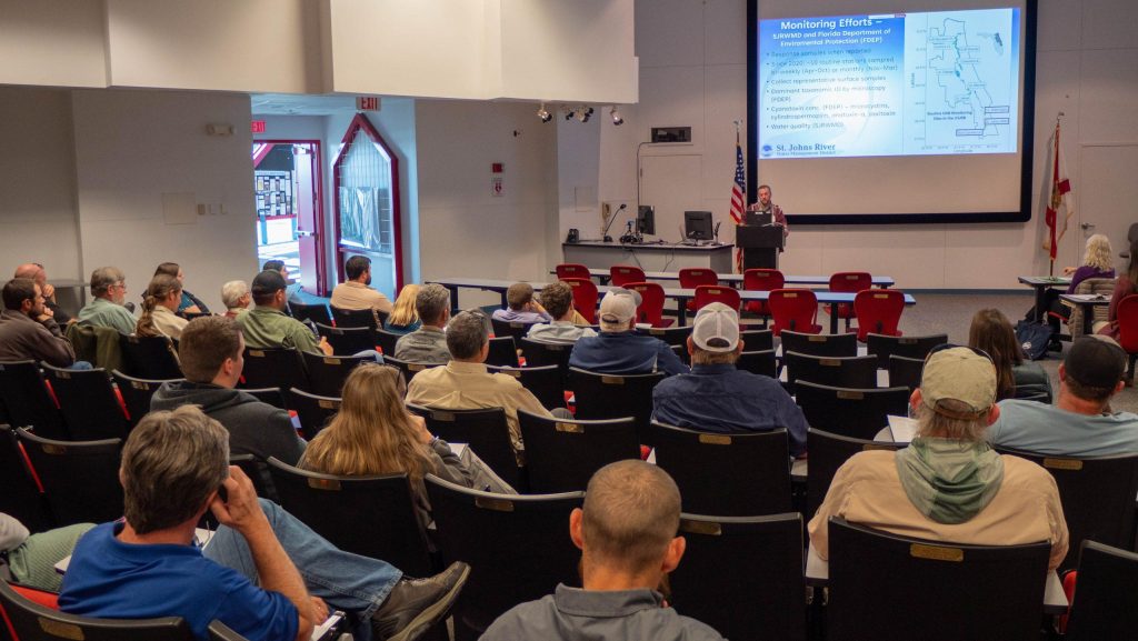 environmental scientist, Josh Papacek, speaking at a podium in front of a room full of people