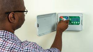 Man in a checkered shirt adjusting an irrigation timer