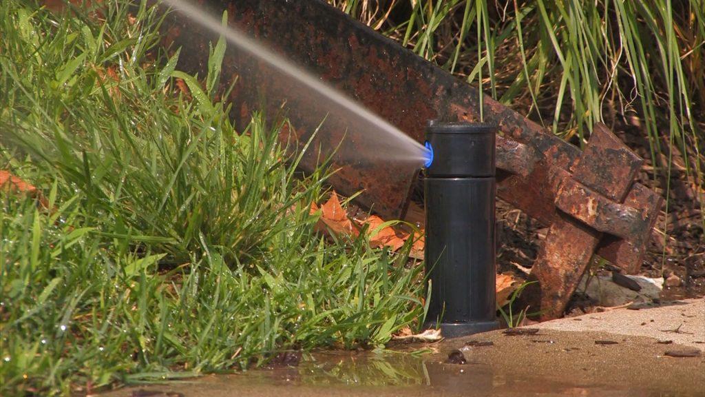 Irrigation sprinkler with water spraying on grass