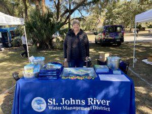 District Education and Outreach Coordinator Ali Pressel standing behind an event table with promotional district items on it.
