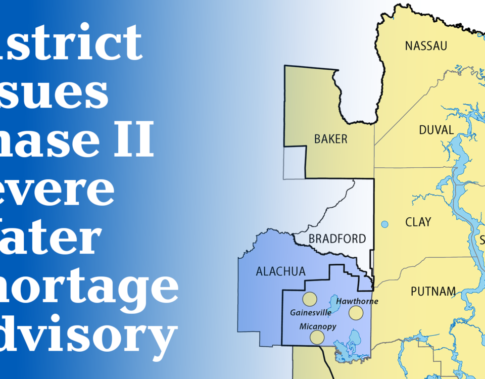 A map graphic announcing a Phase II Severe Water Shortage Advisory issued by the water management district, showing the affected area highlighted in blue covering Alachua and Bradford counties, with cities Gainesville, Micanopy, and Hawthorne marked, surrounded by the yellow-shaded counties of Nassau, Baker, Duval, Clay, St. Johns, Putnam, and Flagler within the district boundary