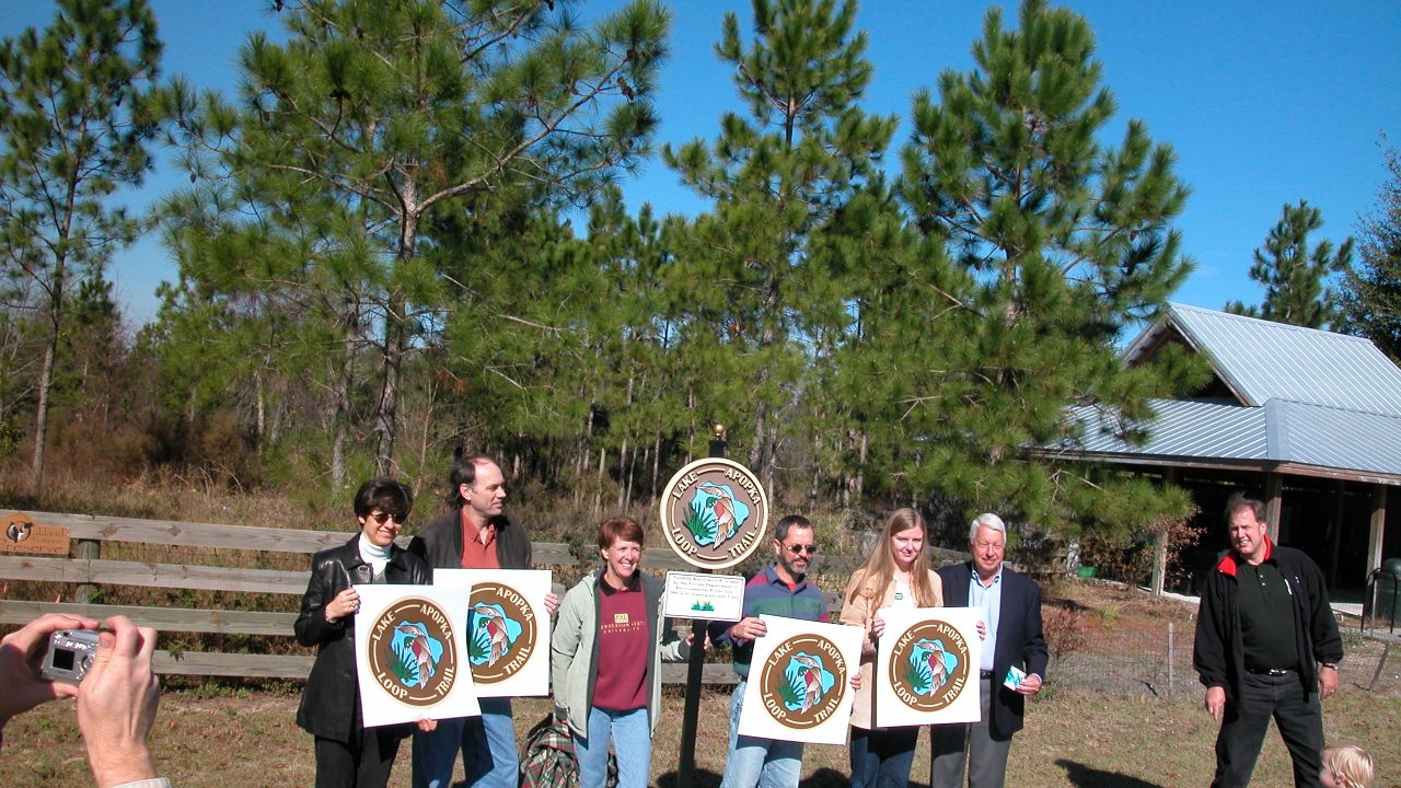 group of people holding signs for the lake apopka loop trail