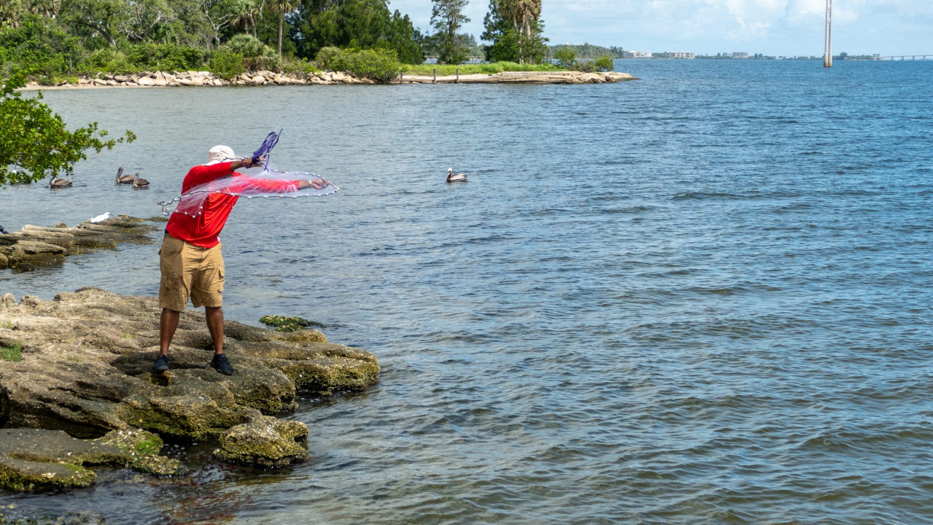 Lagoon – recreation a fisherman in a red shirt casting a net into the water
