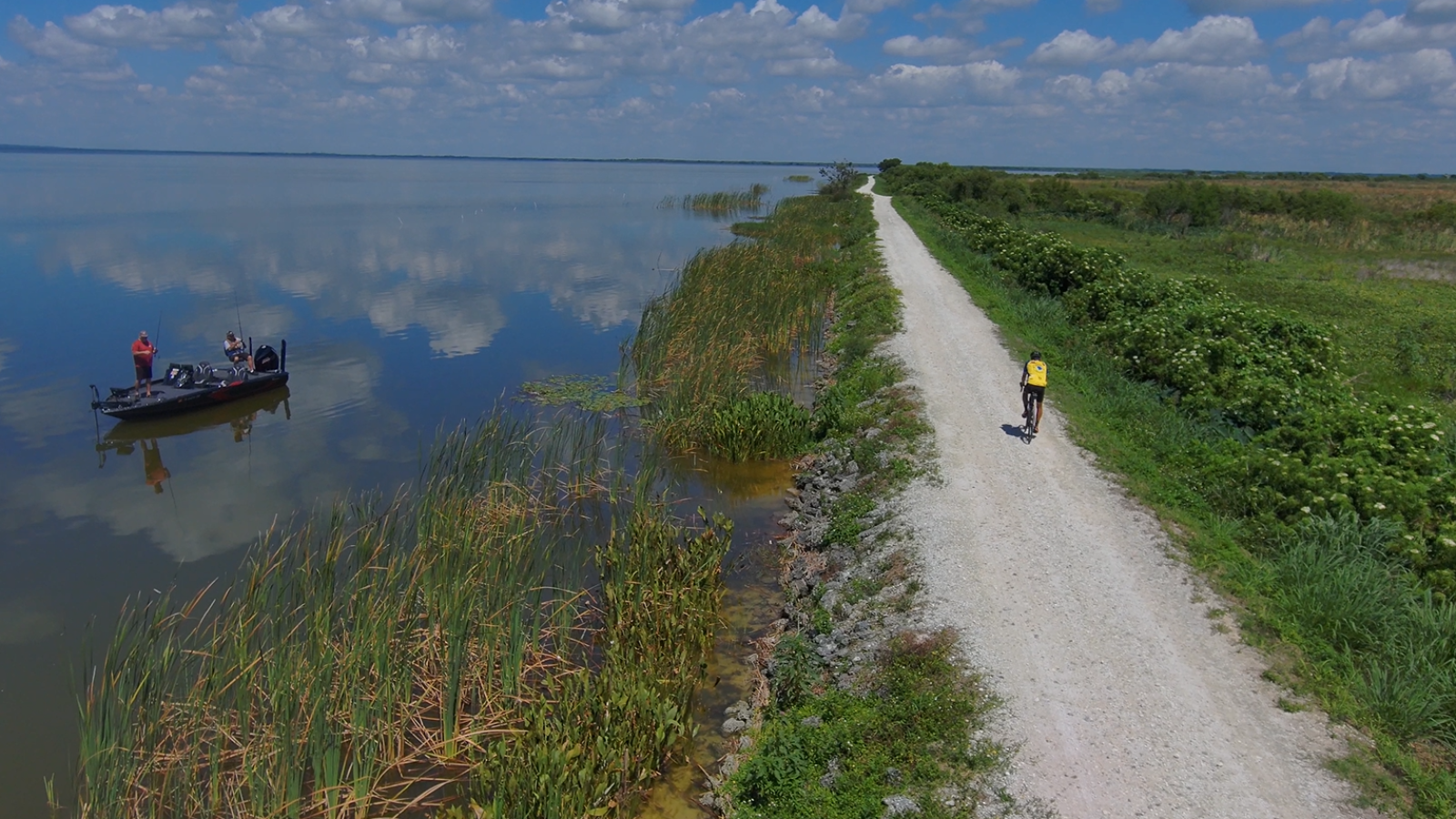 LakeApopkaLoopTrail A cyclist rides along the Lake Apopka Loop Trail on the Lake Apopka North Shore as anglers fish nearby on Lake Apopka.